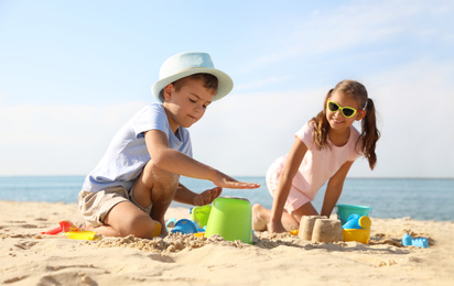 Photo of Cute little children playing with plastic toys on sandy beach