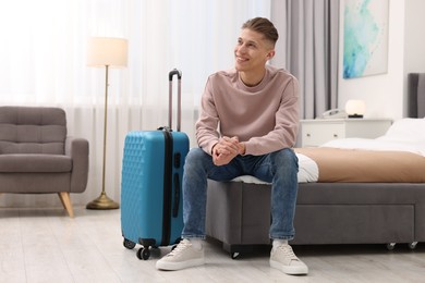 Smiling guest relaxing on bed in stylish hotel room