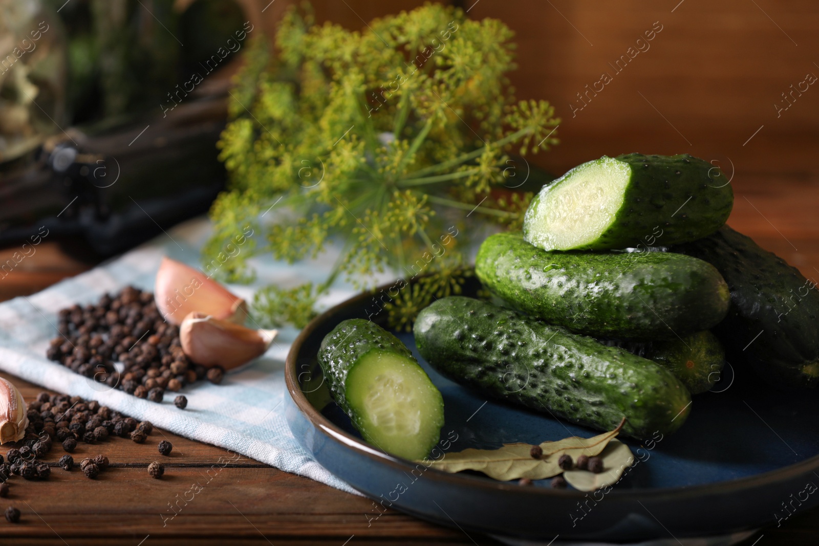 Photo of Fresh cucumbers and other ingredients prepared for canning on wooden table, closeup