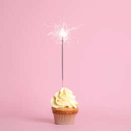 Birthday cupcake with sparkler on pink background