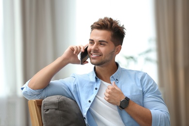 Photo of Portrait of handsome young man talking on phone in room