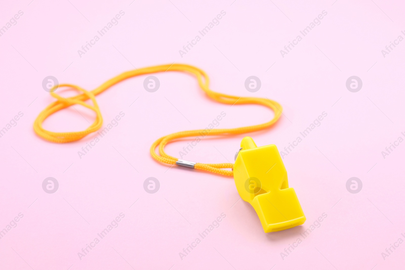 Photo of One yellow whistle with orange cord on pink background
