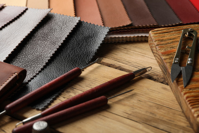 Photo of Leather samples and tools on wooden table, closeup