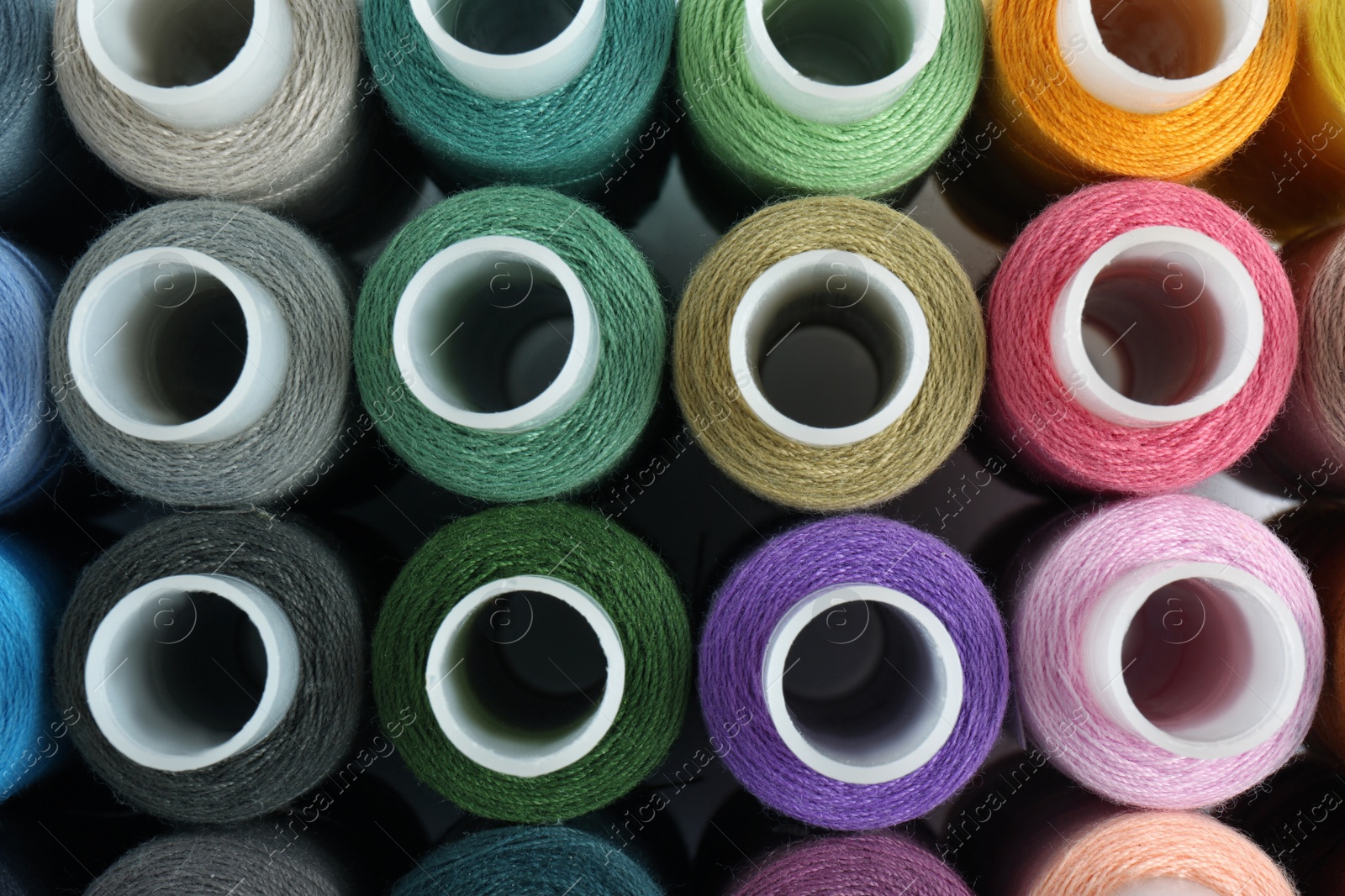 Photo of Set of colorful sewing threads as background, top view