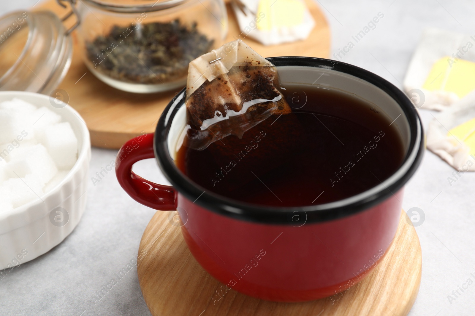 Photo of Brewing tea. Cup with tea bag on light table, closeup