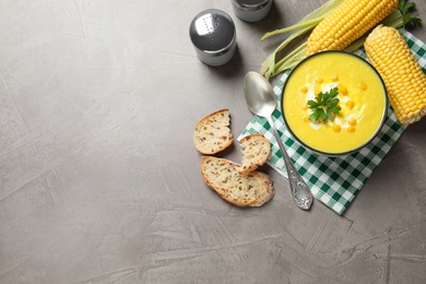 Delicious creamy corn soup served on grey table, flat lay. Space for text