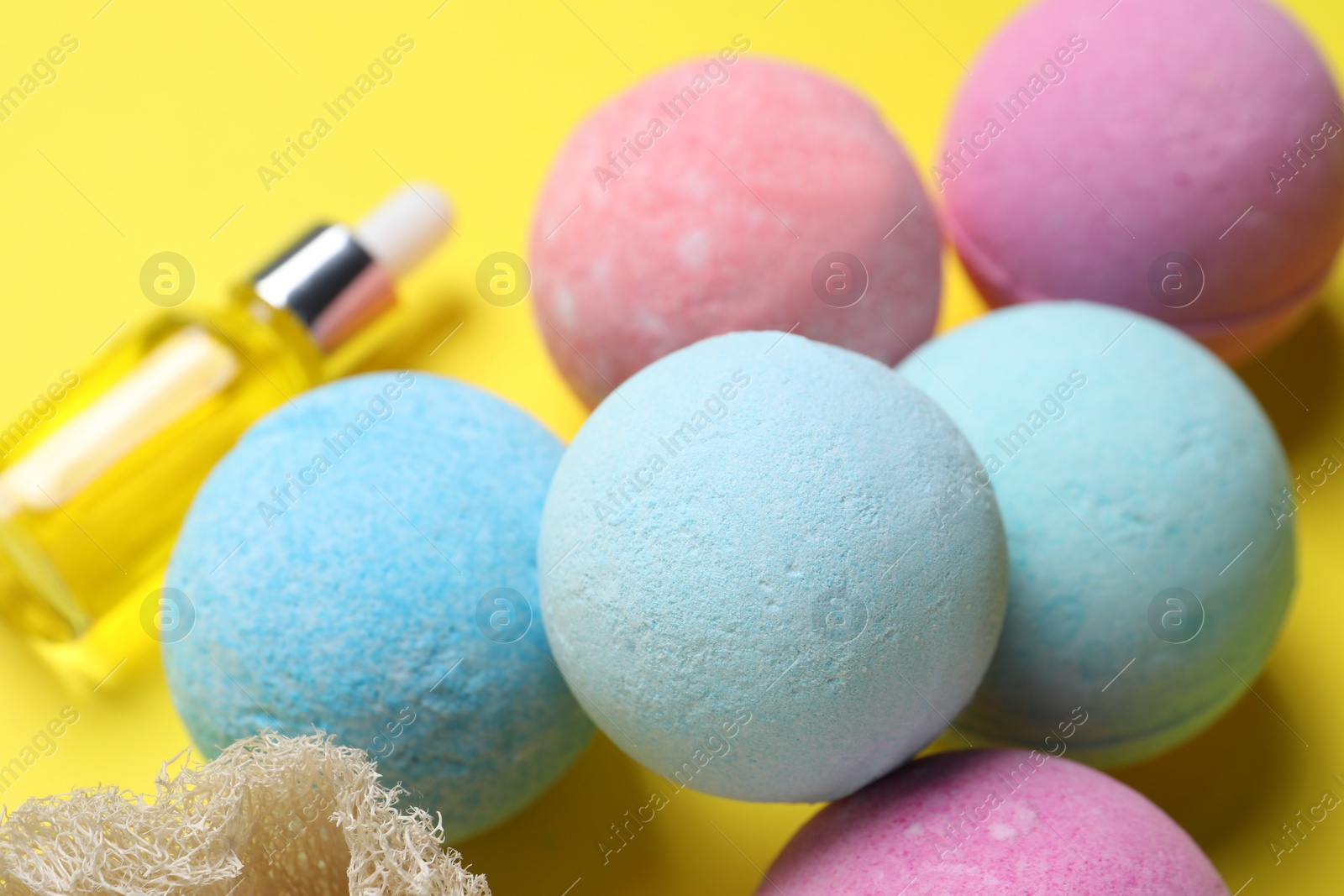 Photo of Bath bombs and bottle on yellow background, closeup