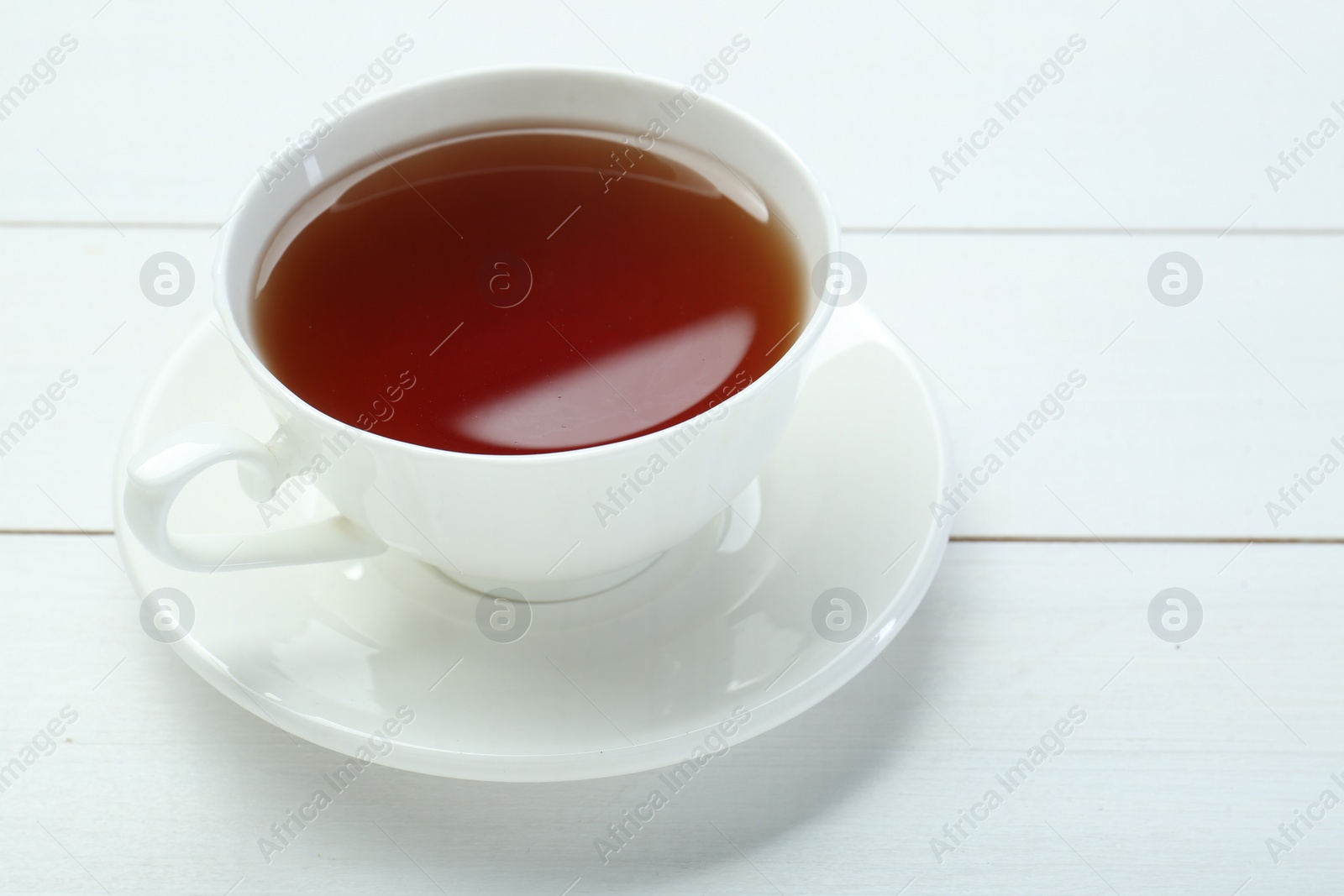 Photo of Aromatic tea in cup on white wooden table