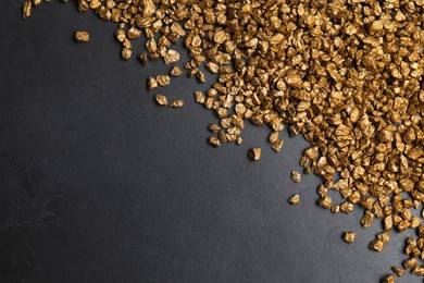 Photo of Pile of gold nuggets on black table, flat lay. Space for text