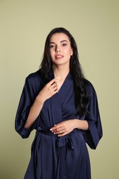 Photo of Pretty young woman in dark blue silk robe on light background