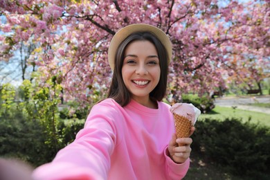 Happy woman taking selfie with ice cream in spring park