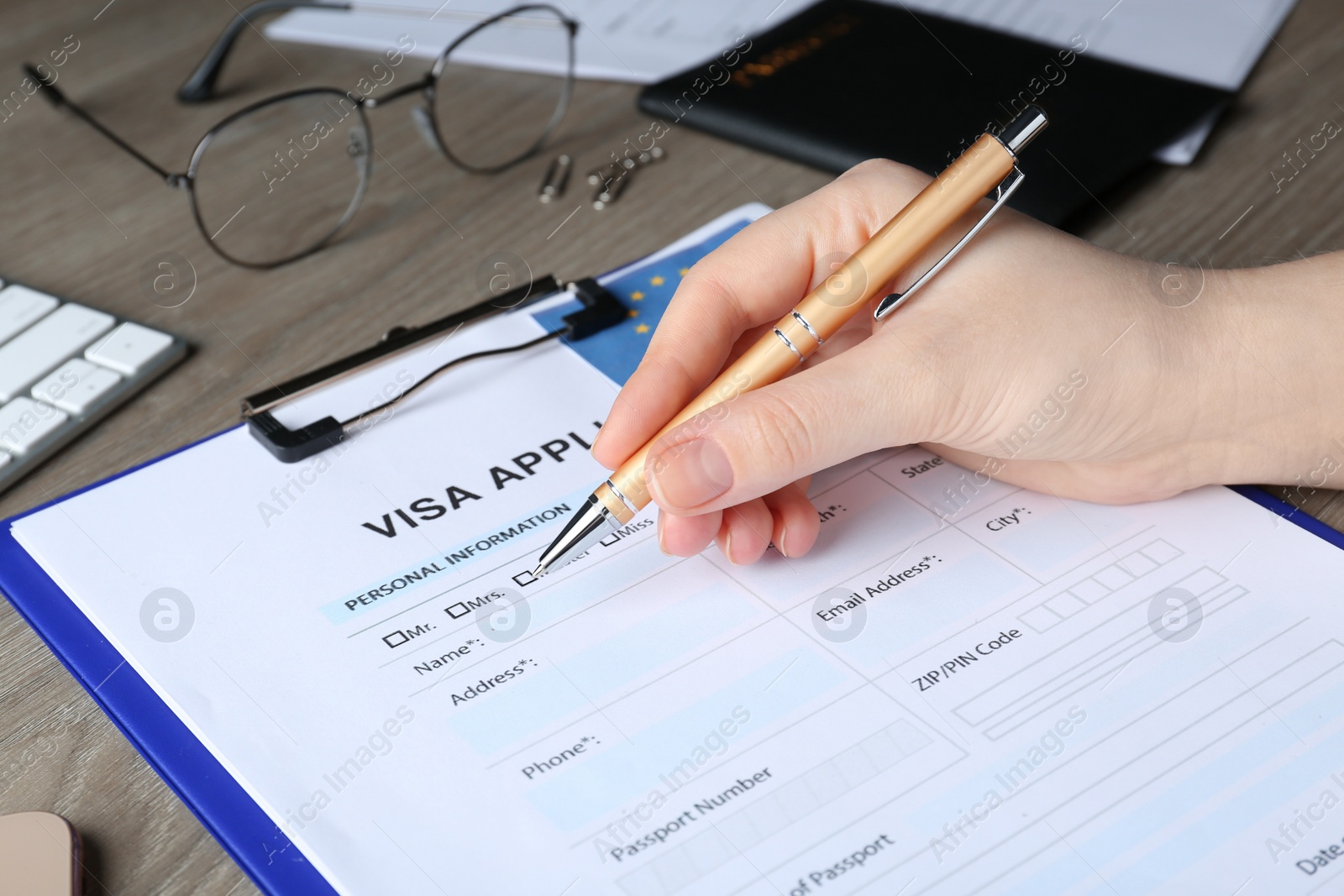 Photo of Woman filling visa application form for immigration to European Union at wooden table, closeup