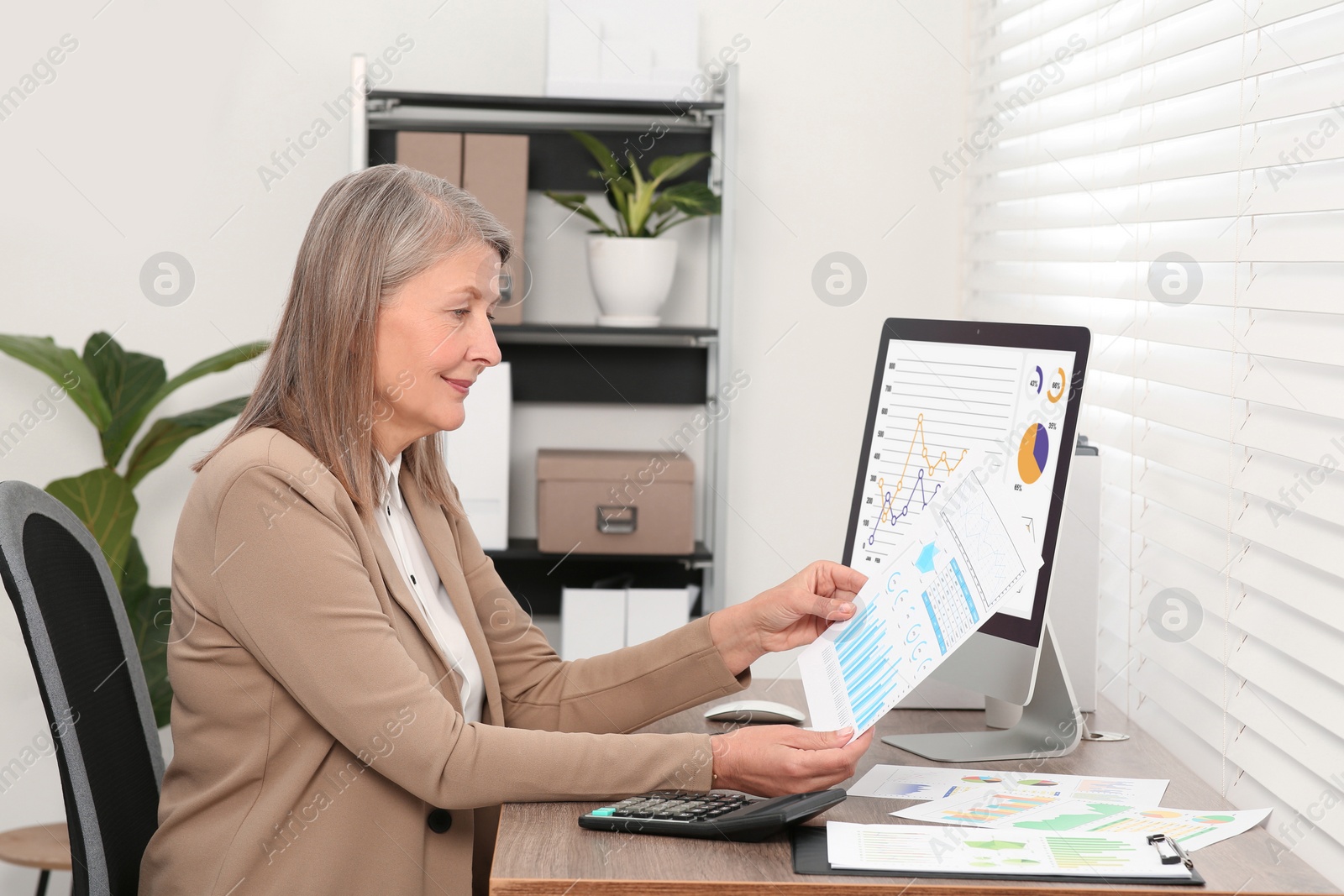 Photo of Senior accountant working at wooden desk in office