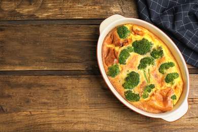 Photo of Tasty broccoli casserole in baking dish on wooden table, top view. Space for text