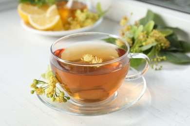 Photo of Cup of tea with linden blossom on white windowsill