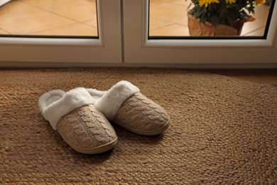 Photo of Pair of beautiful soft slippers on wicker mat in room. Space for text