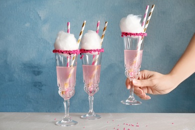 Photo of Woman taking glass with cocktail and candy cotton from table, closeup