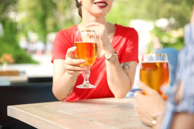 Young women with glasses of cold beer at table