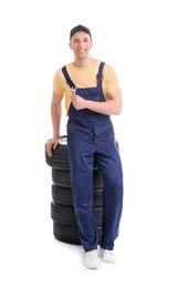 Photo of Male mechanic with car tires on white background