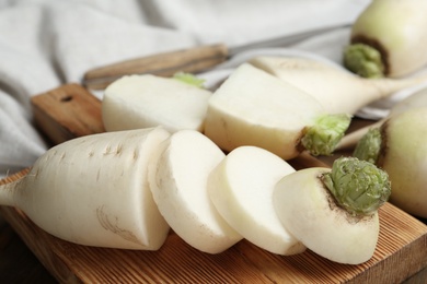 Photo of Cut white turnip on wooden board, closeup