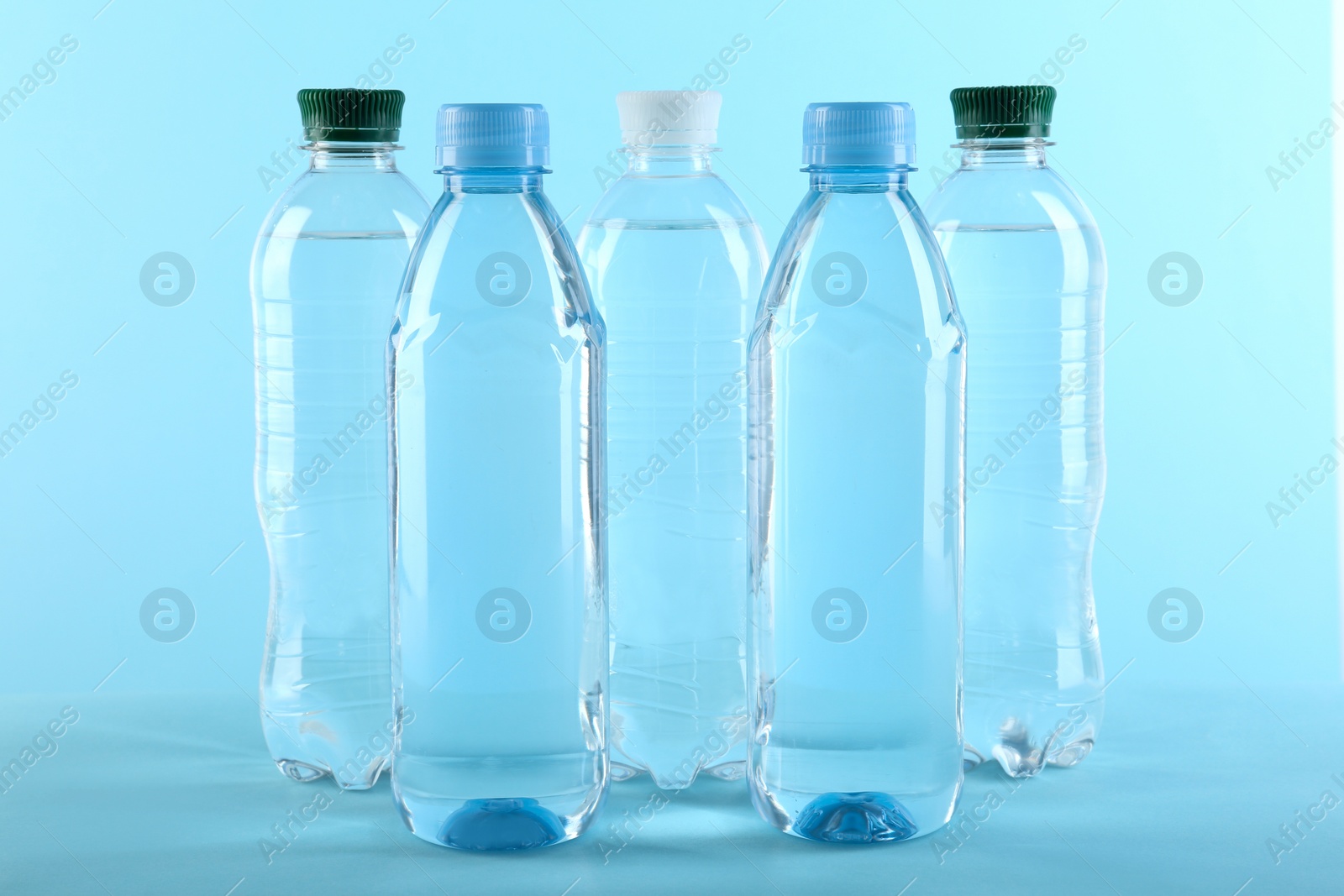 Photo of Set of different plastic bottles with water on blue background