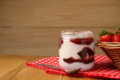 Photo of Tasty yoghurt with jam, spoon and strawberries on wooden table, closeup. Space for text