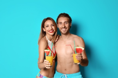 Photo of Happy young couple in beachwear with cocktails on color background
