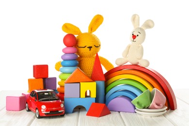 Different children's toys on wooden table against white background