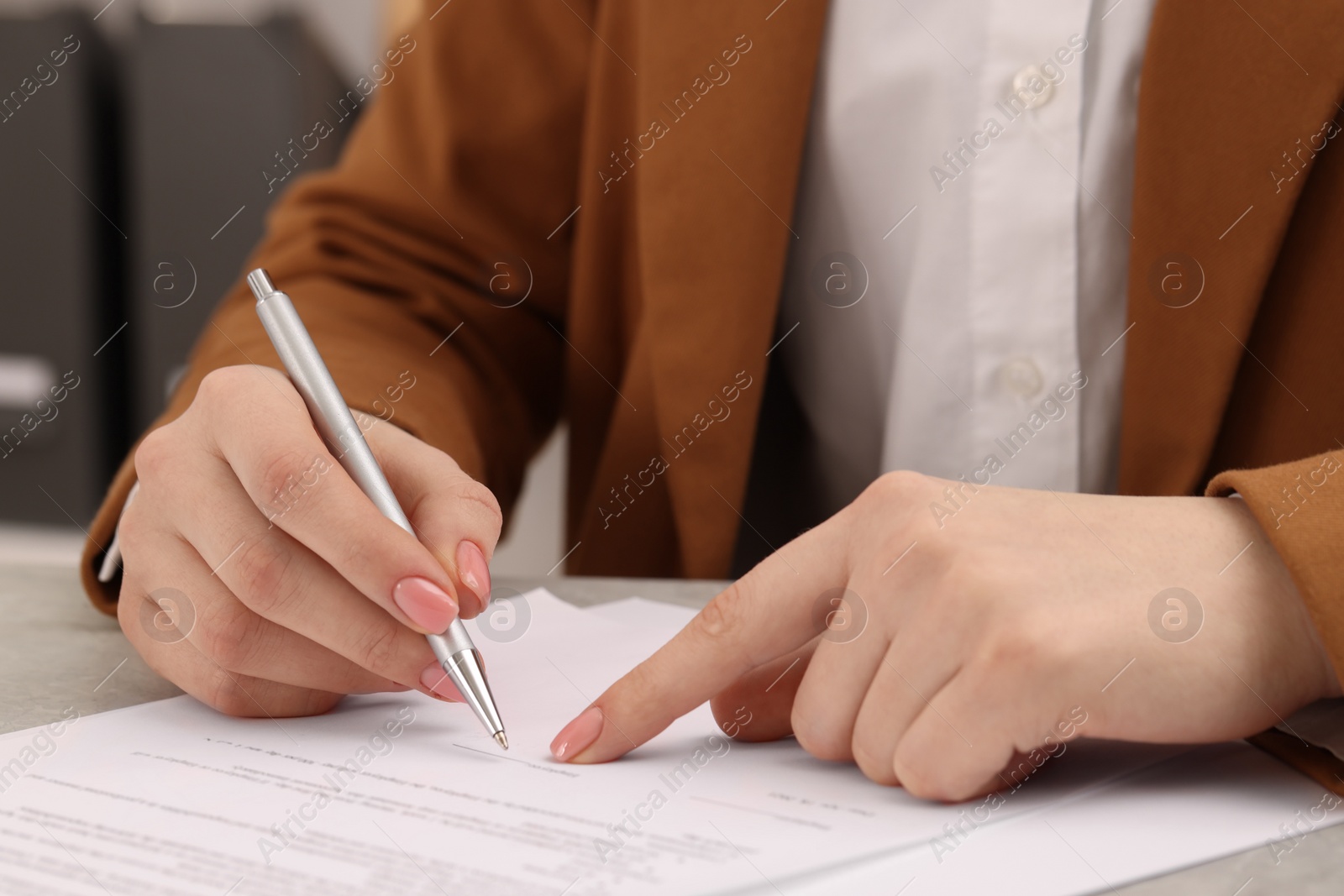 Photo of Woman signing document at table, closeup view