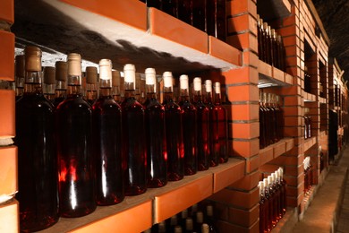 Photo of Many bottles of alcohol drinks on shelves in cellar