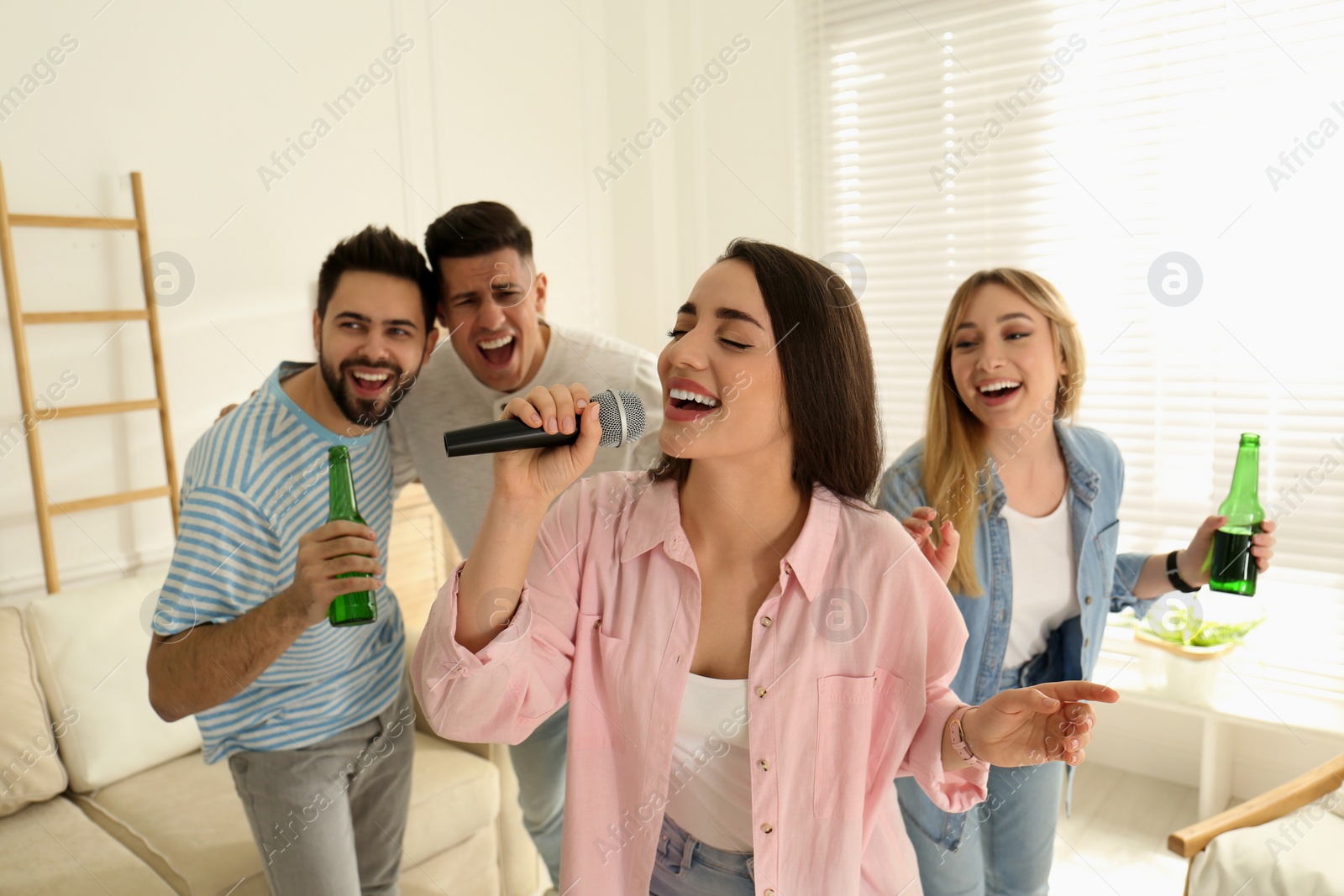 Photo of Young woman singing karaoke with friends at home