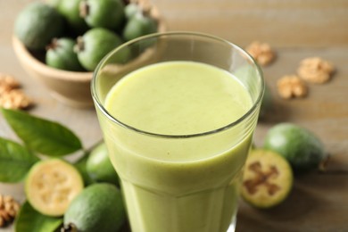 Photo of Fresh feijoa smoothie in glass on table, closeup view