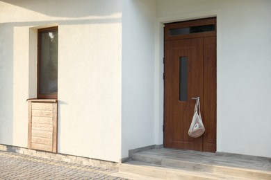 Photo of Helping neighbours. Net bag of products hanging on door outdoors