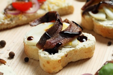 Delicious sandwiches with anchovies on wooden table, closeup