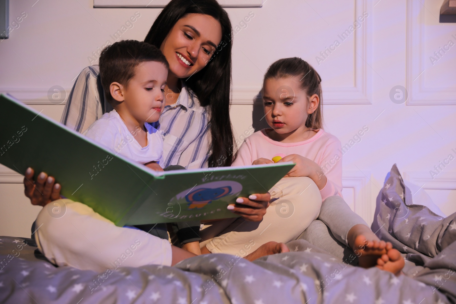 Photo of Mother reading bedtime story to her children at home