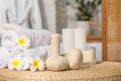 Photo of Herbal bags, candles, rolled towels and beautiful flowers on wicker surface indoors. Spa products