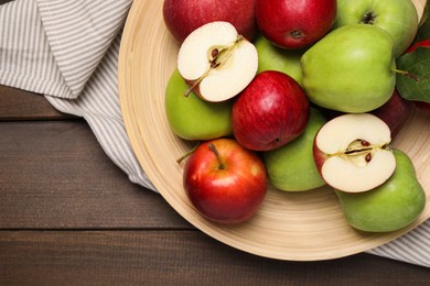 Photo of Plate with fresh ripe apples and leaves on wooden table, top view. Space for text