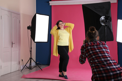 Photographer taking picture of overweight woman in studio. Plus size model