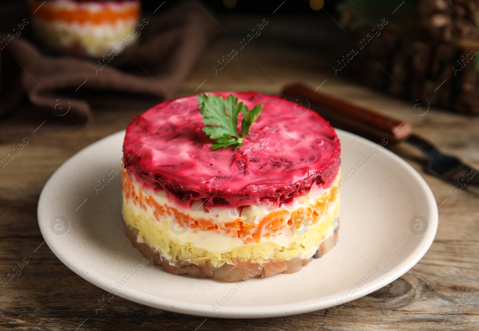 Photo of Herring under fur coat served on wooden table, closeup. Traditional russian salad