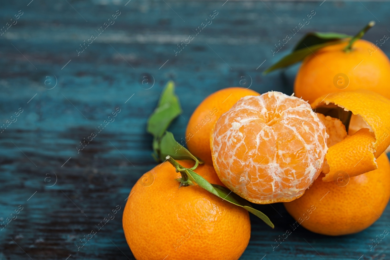 Photo of Fresh ripe tangerines with green leaves on table. Space for text