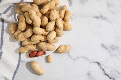 Photo of Fresh unpeeled peanuts on white marble table, top view. Space for text