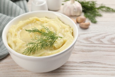 Photo of Bowl of tasty mashed potato with garlic and dill on wooden table, closeup. Space for text