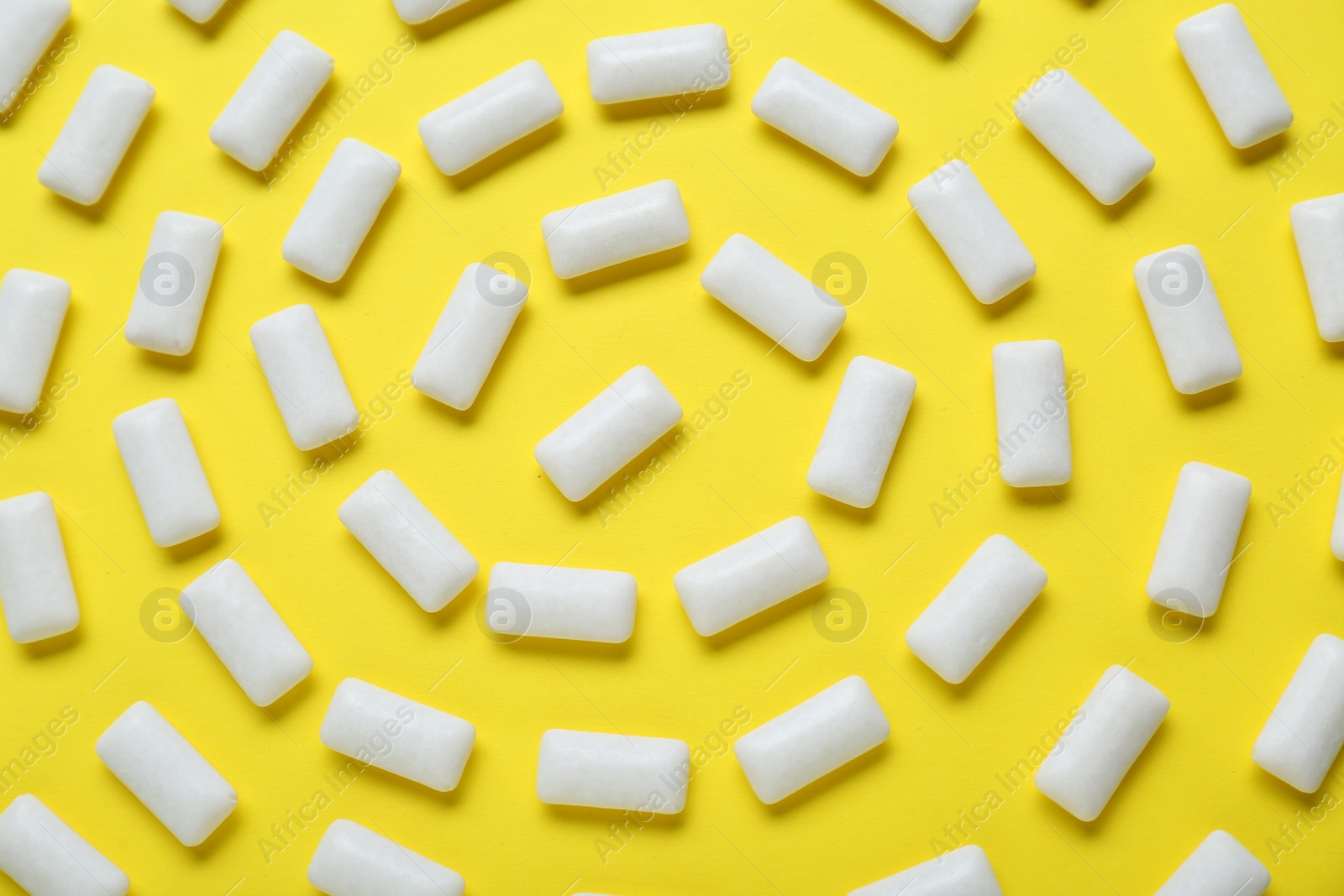 Photo of Tasty white chewing gums on yellow background, flat lay