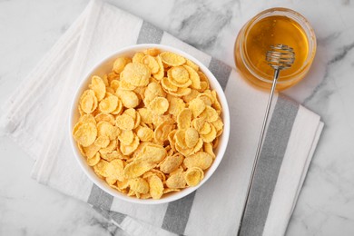 Photo of Tasty crispy corn flakes in bowl and honey on white marble table, flat lay. Breakfast cereal