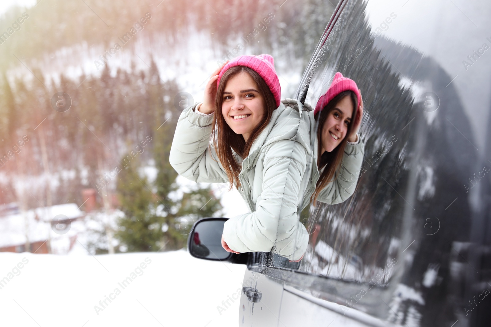 Photo of Happy young woman looking out of car window on road. Winter vacation