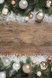 Fir branches, Christmas decoration and snow on wooden background, flat lay. Space for text