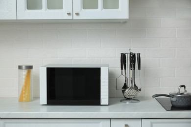 Photo of Modern microwave oven on countertop in kitchen