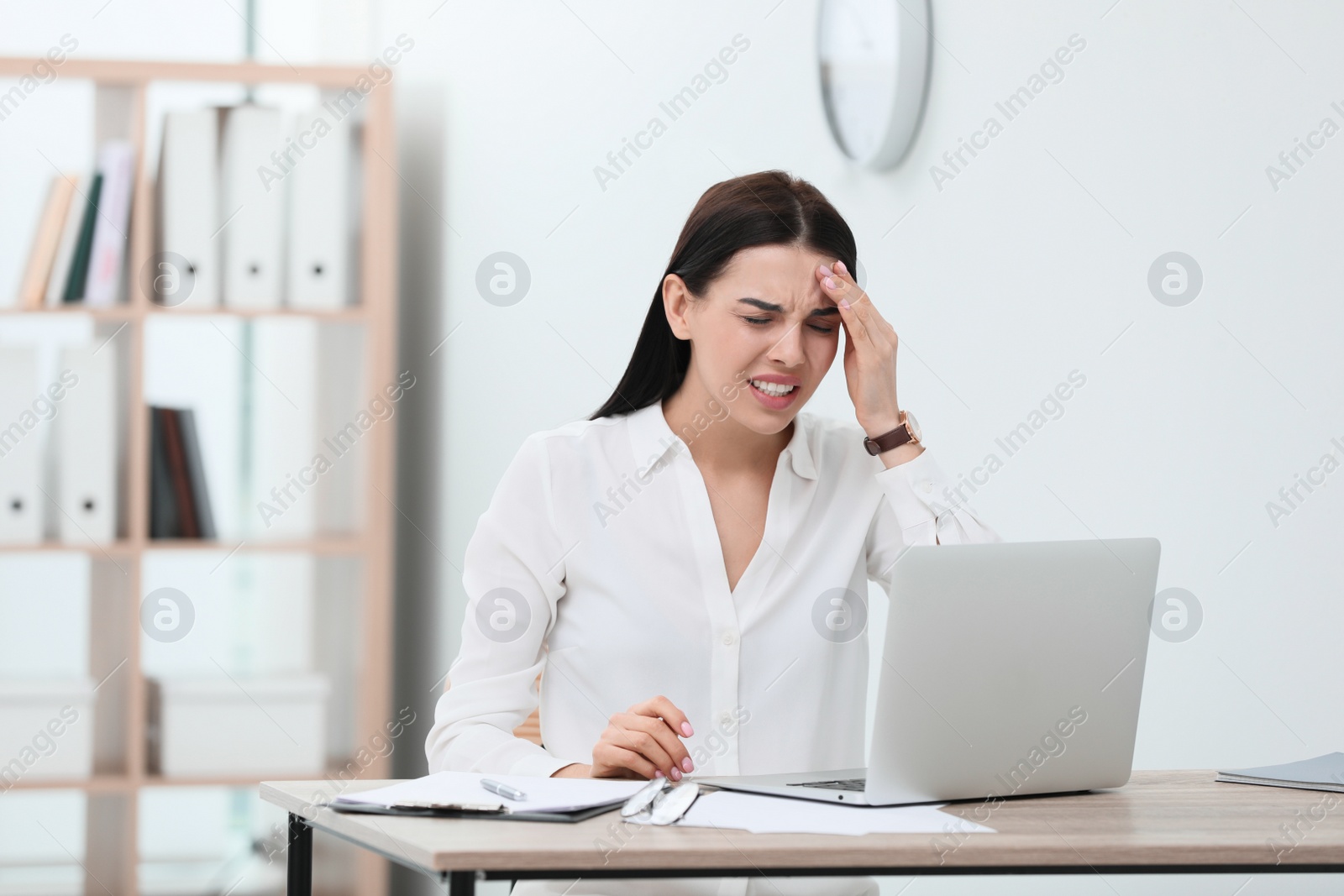 Photo of Woman suffering from migraine at workplace in office