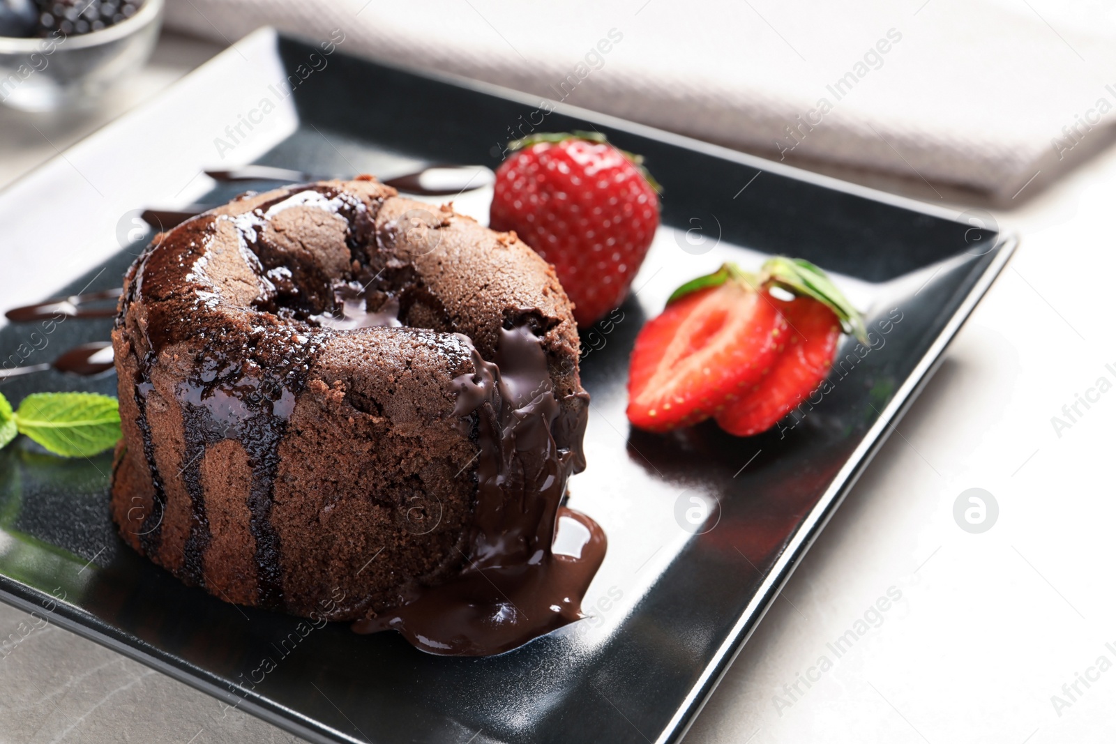 Photo of Plate of delicious fresh fondant with hot chocolate and strawberries on table. Lava cake recipe