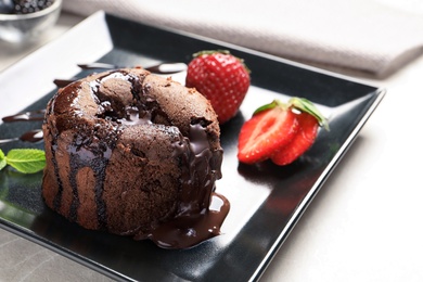 Plate of delicious fresh fondant with hot chocolate and strawberries on table. Lava cake recipe